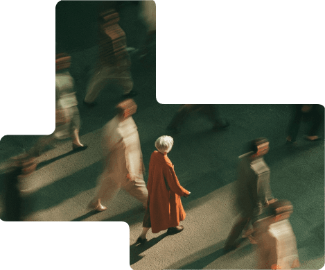 A crowd walking, seen from above, with one figure in an orange coat in focus