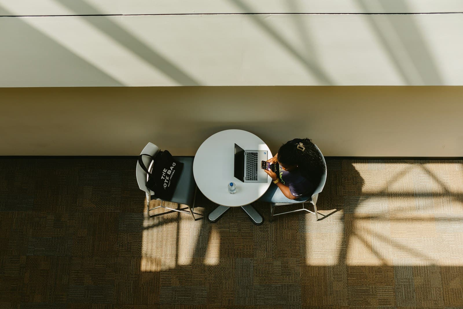 Two people at a round table in a shaft of sunlight, seen from above